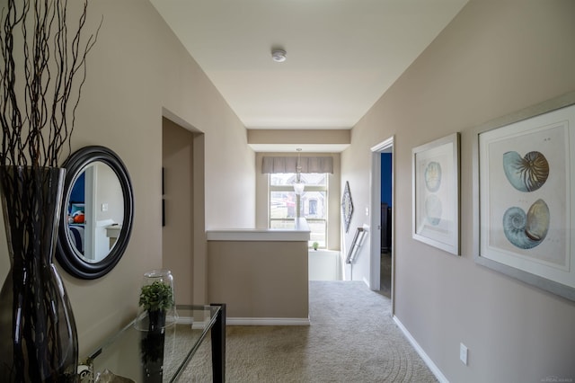 hallway featuring an upstairs landing, baseboards, and carpet floors