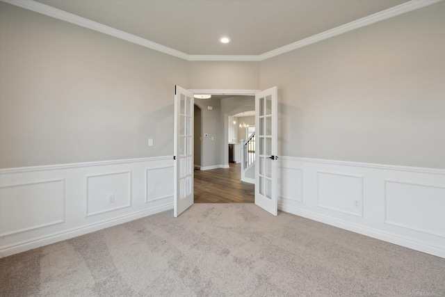 carpeted spare room featuring recessed lighting, french doors, ornamental molding, and wainscoting