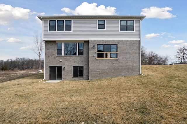 rear view of house featuring brick siding and a yard