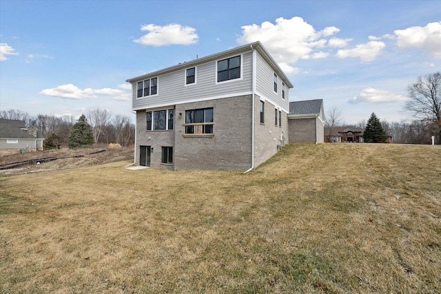 back of house with brick siding and a lawn