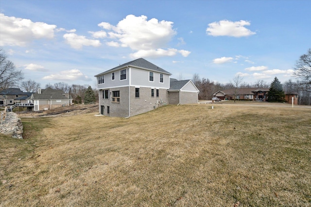 rear view of house featuring brick siding and a yard