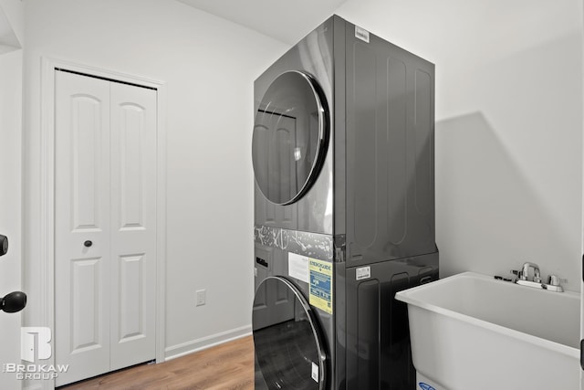 laundry area featuring stacked washer / drying machine, sink, and hardwood / wood-style floors