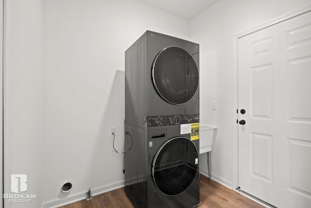 laundry room with stacked washer / dryer and dark hardwood / wood-style flooring