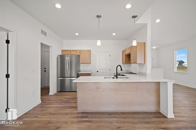 kitchen featuring hardwood / wood-style floors, stainless steel refrigerator, sink, and kitchen peninsula