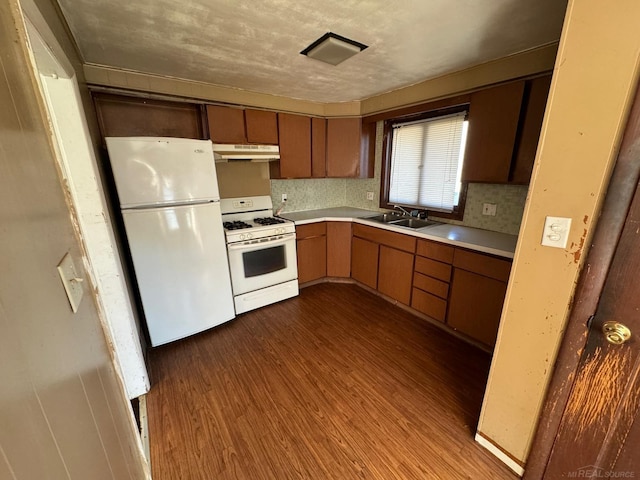 kitchen featuring dark hardwood / wood-style floors, white appliances, backsplash, and sink