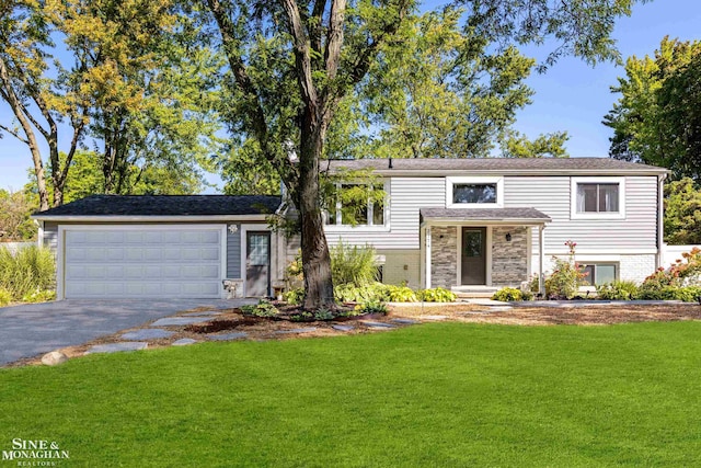 raised ranch featuring a garage and a front lawn