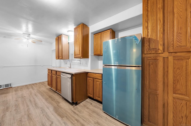 kitchen featuring decorative backsplash, light wood-type flooring, stainless steel appliances, ceiling fan, and sink