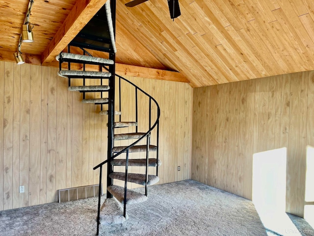 stairs with carpet flooring, lofted ceiling with beams, rail lighting, and wood walls