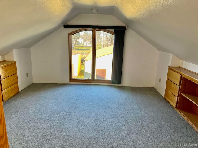 bonus room with a textured ceiling, lofted ceiling, and carpet floors