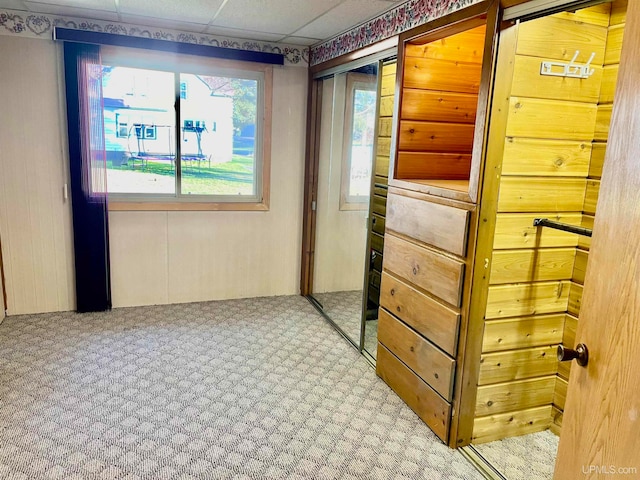 corridor with a paneled ceiling and carpet floors