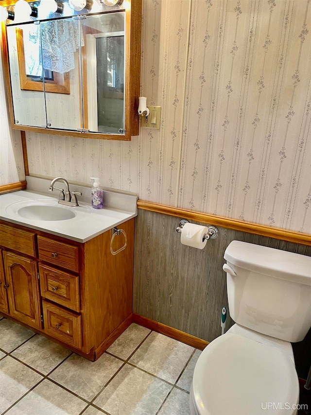 bathroom with wood walls, vanity, tile patterned floors, and toilet