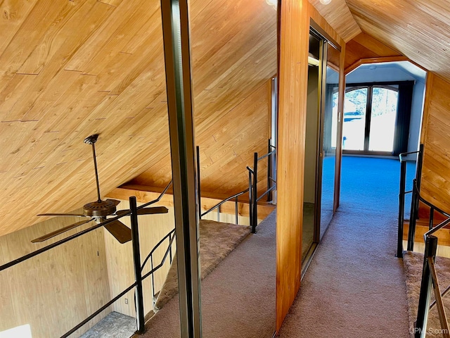 hall featuring wood walls, vaulted ceiling, and dark carpet