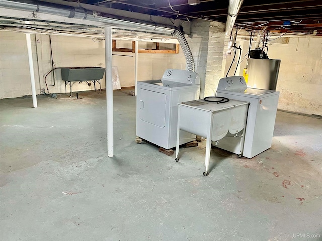 basement featuring water heater, washer and clothes dryer, and sink