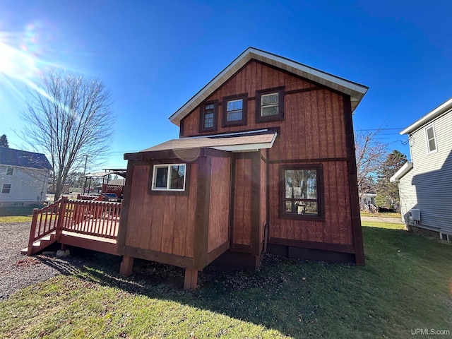 rear view of house with a wooden deck and a lawn