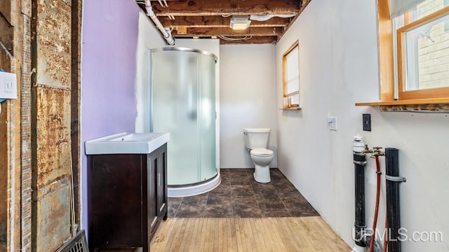 bathroom with toilet, hardwood / wood-style floors, an enclosed shower, vanity, and gas water heater