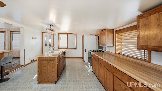 kitchen featuring an inviting chandelier, appliances with stainless steel finishes, sink, and a center island with sink