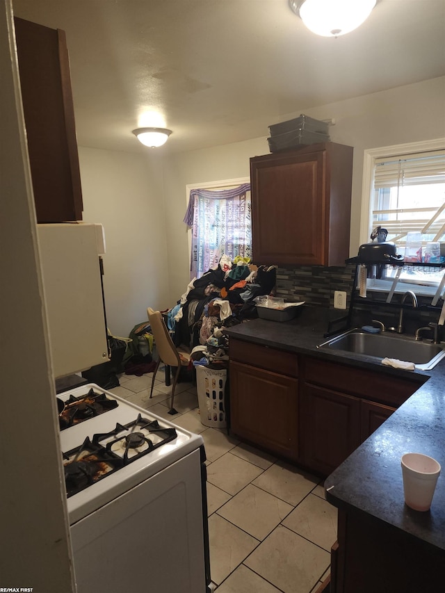 kitchen with light tile patterned floors, white appliances, sink, and tasteful backsplash