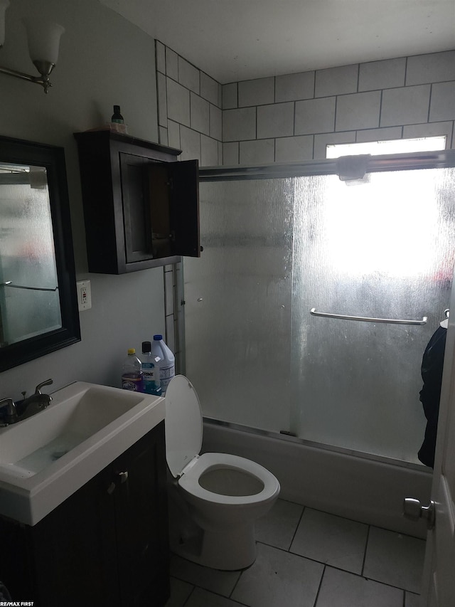 full bathroom with tile patterned flooring, plenty of natural light, combined bath / shower with glass door, and toilet