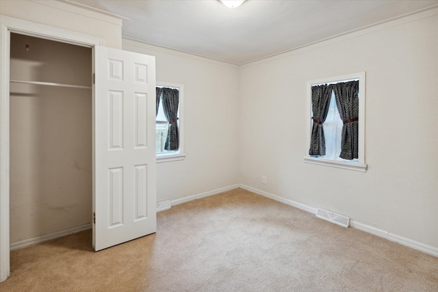 unfurnished bedroom featuring a closet, light carpet, and ornamental molding