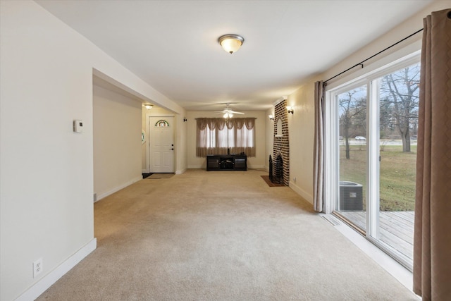 interior space with a brick fireplace, light carpet, and ceiling fan