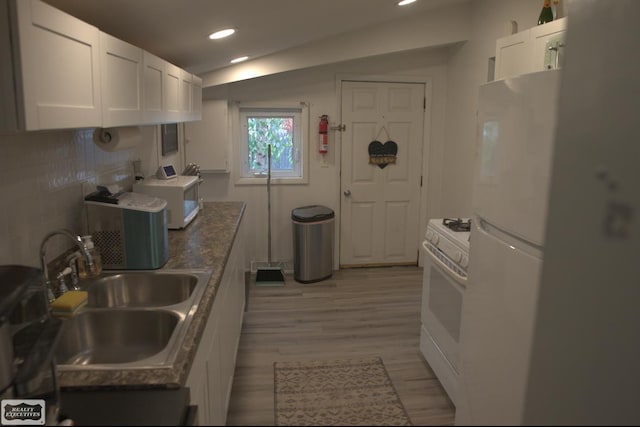 kitchen with light wood-type flooring, sink, white cabinets, dark stone countertops, and white appliances