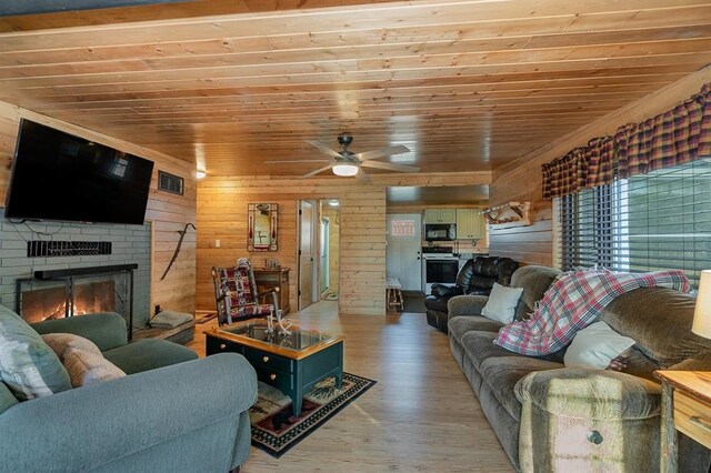 living room featuring wooden walls, a fireplace, hardwood / wood-style floors, wood ceiling, and ceiling fan