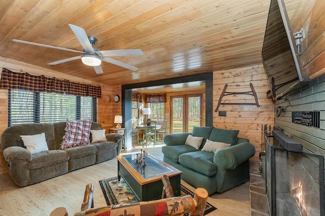 living room with a brick fireplace, wood walls, a healthy amount of sunlight, and light wood-type flooring