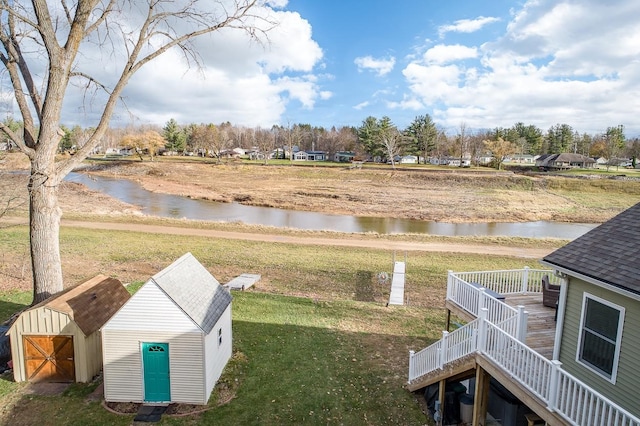 view of yard with a deck with water view and a storage shed