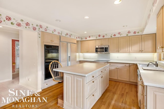 kitchen featuring crown molding, sink, black appliances, light hardwood / wood-style floors, and a kitchen island