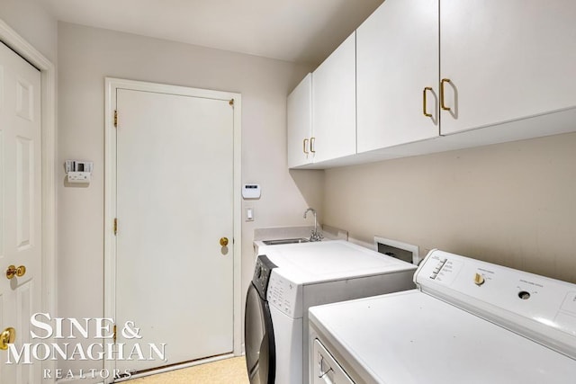 washroom with sink, washing machine and dryer, and cabinets