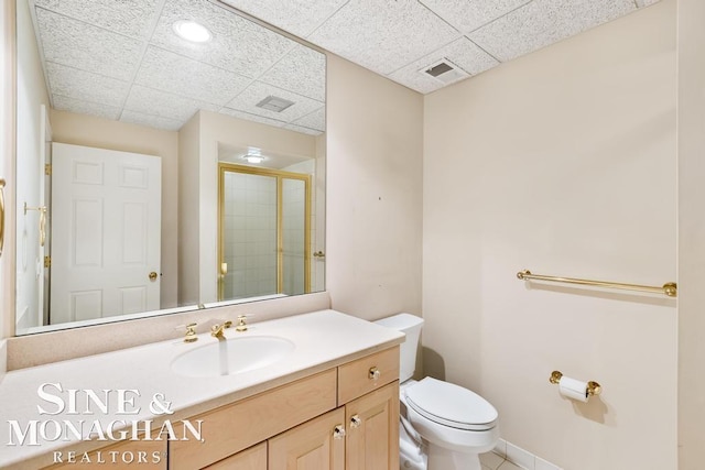 bathroom featuring tile patterned floors, walk in shower, a drop ceiling, vanity, and toilet