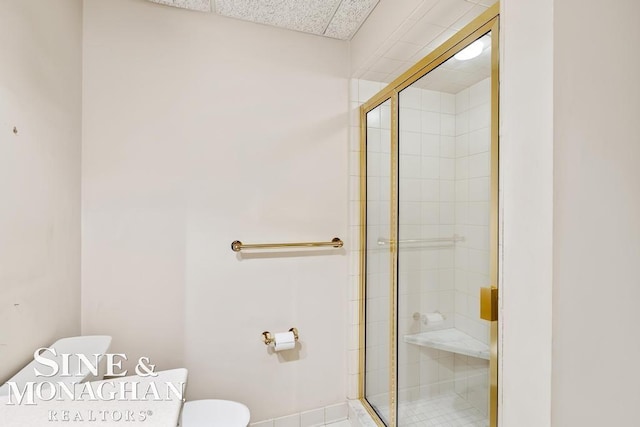 bathroom featuring a shower with door and toilet