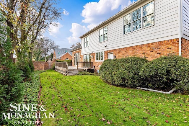 rear view of house featuring a lawn and a deck