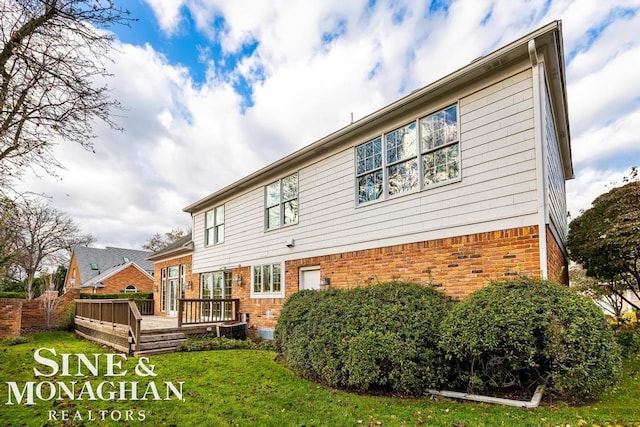 back of property featuring a deck and a lawn