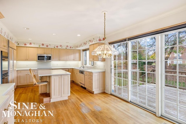 kitchen with light hardwood / wood-style flooring, light brown cabinets, a kitchen island, hanging light fixtures, and crown molding