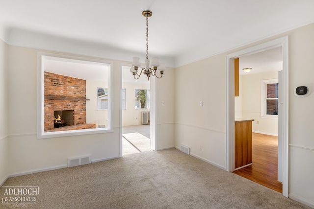 unfurnished dining area featuring a fireplace, a notable chandelier, and carpet floors