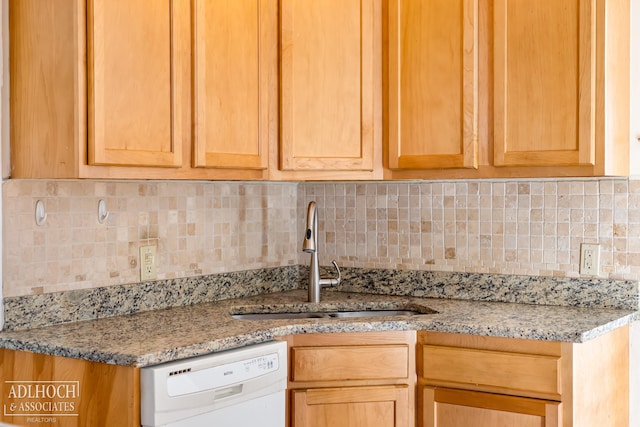 kitchen with backsplash, light stone countertops, dishwasher, and sink