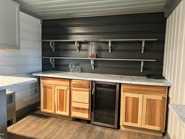 bar featuring light hardwood / wood-style floors, light stone countertops, and beverage cooler