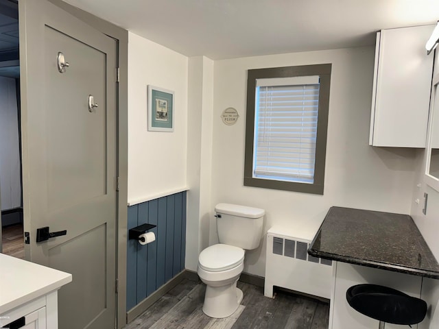 bathroom featuring toilet, radiator heating unit, vanity, and hardwood / wood-style flooring