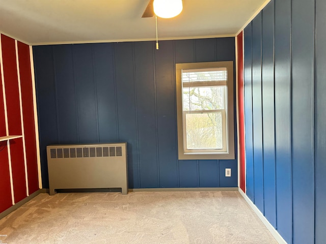 carpeted empty room featuring radiator, crown molding, and ceiling fan