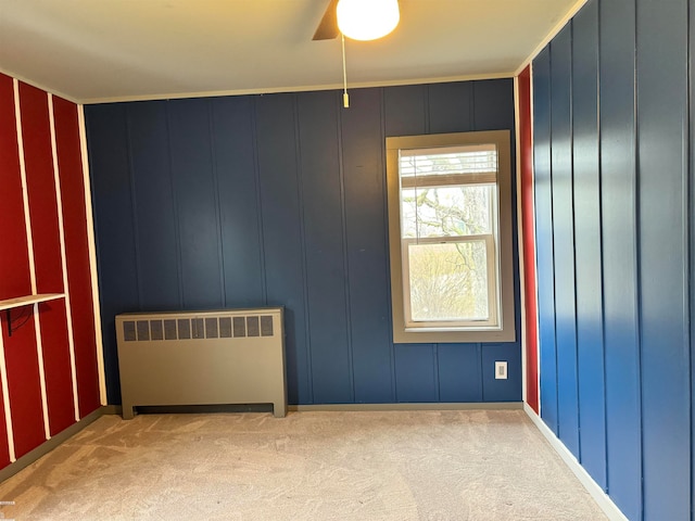 carpeted spare room featuring radiator, ceiling fan, and crown molding