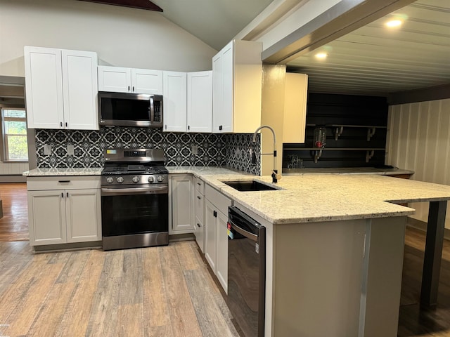 kitchen featuring white cabinetry, a kitchen bar, kitchen peninsula, and stainless steel appliances