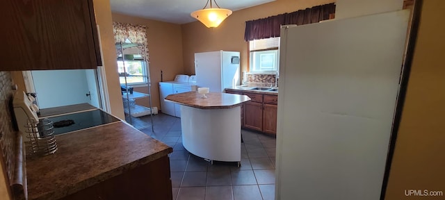 kitchen featuring decorative light fixtures, a kitchen island, a healthy amount of sunlight, and white refrigerator