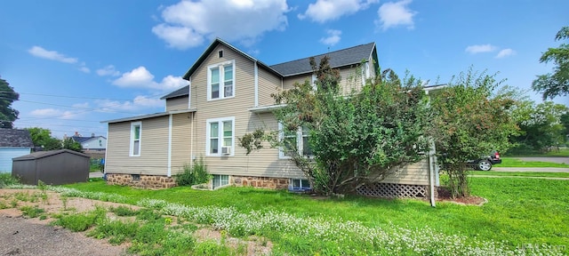 back of house with a storage shed and a yard