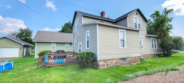 back of house with an outbuilding, a garage, a lawn, and a wooden deck