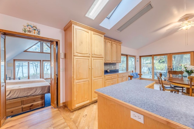 kitchen with light brown cabinetry, light hardwood / wood-style floors, a healthy amount of sunlight, and vaulted ceiling with skylight