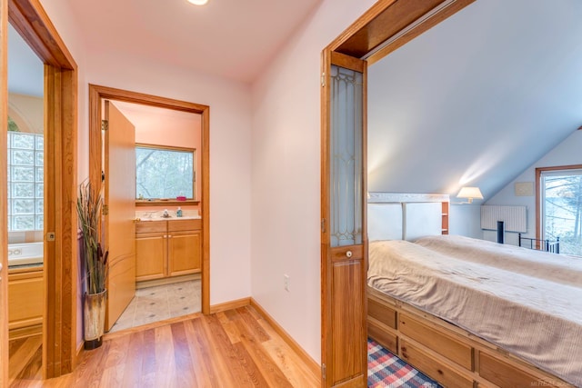 bedroom featuring ensuite bath, lofted ceiling, and light hardwood / wood-style flooring