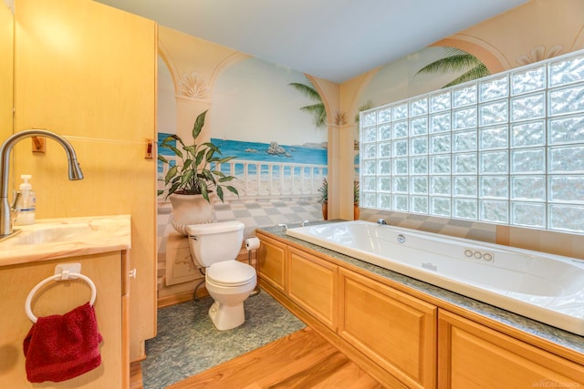 bathroom with a washtub, hardwood / wood-style floors, vanity, and toilet