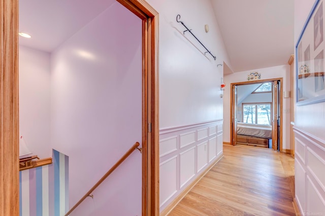 hallway with lofted ceiling and light hardwood / wood-style flooring