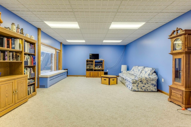 living area with carpet and a paneled ceiling